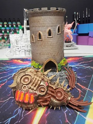 A painted stone dice tower beside a bronze mechanical creature with glowing vents
