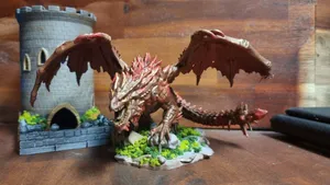 A hand-painted dragon miniature with outstretched wings on a flocked base, castle tower behind